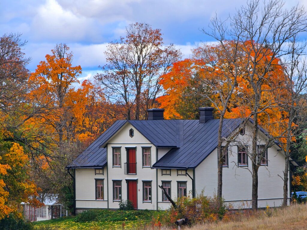 Scenic view of a traditional Swedish house surrounded by vibrant autumn foliage in Uppsala, Sweden.